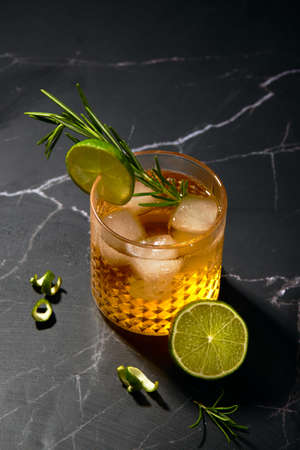 Alcoholic or non-alcoholic cocktail with lime and rosemary on a dark marble table.の写真素材