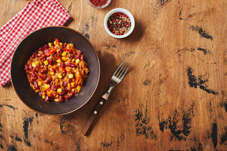 Chili Con Carne with ground beef, beans and corn in dark bowl on wooden background. Mexican and Texas cuisineの写真素材