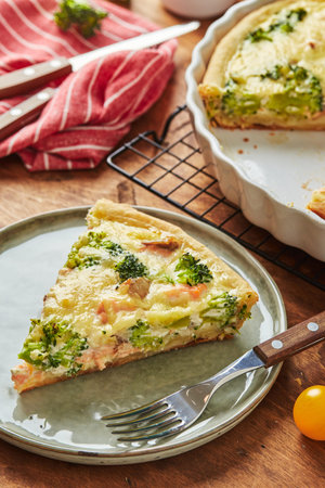 Homemade quiche with red fish, salmon, broccoli and cheese on wooden background