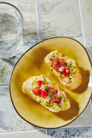 Crostini or bruschetta with softened avocado, ham and tomatoes. Toast with mashed avocadoの写真素材
