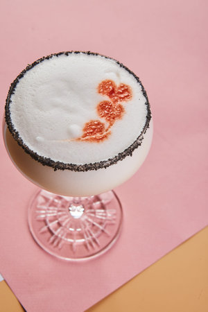 Cold alcoholic or non-alcoholic cocktail with foam on pastel background. Hard light, deep shadow.