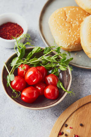 Cherry tomatoes and green pea sprouts in bowl on the tableの写真素材