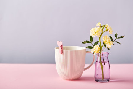 Flower of yellow matthiola in little glass vase with white cup. Design concept of holiday greeting...