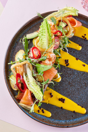 Beautiful restaurant serving dishes of red fish and vegetables and sauceの写真素材