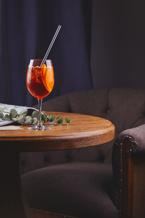 Aperol Spritz cocktail with ice in glass on wooden table in dark interior.の写真素材