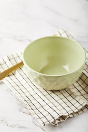 Empty green bowl on napkin on white tableの写真素材