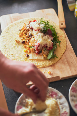 Cooking burrito, Mexican food at home. Grilled wheat tortilla stuffed with cheese, chicken, beans,...