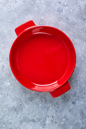 Empty red round ceramic baking dish on gray backgroundの写真素材