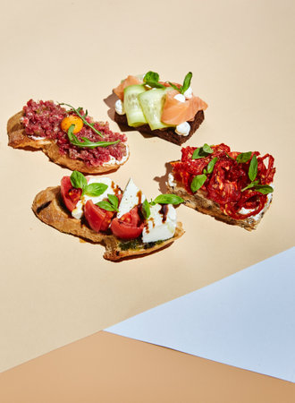 Bruschetta with cream cheese, tomatoes and cucumbers with microgreens on light yellow background. Hard light, deep shadow.の写真素材