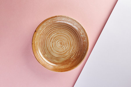 Empty ceramic brown plate on pink background. Mockup, place for text.の写真素材