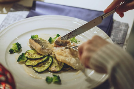 Hands of woman eating fine haute cuisine dish at table in restaurant.の写真素材