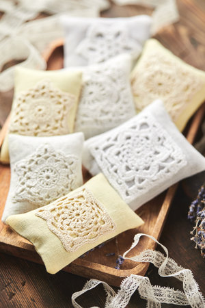 Sachet bags decorated with crocheted lace and lavender on a wooden backgroundの写真素材
