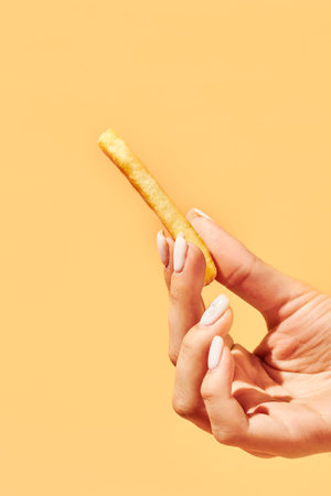 Female hand with tasty French fries on color background
