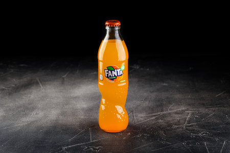 Glass bottle of Coca Cola company soft drink Fanta Orange. Global brand of carbonated soft fruit...