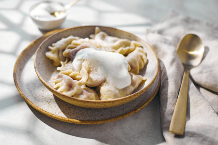 Dumplings with cherries with sour cream and sugar. Traditional dish of Russian, Ukrainian, Belarusian cuisine known as Varenikiの写真素材