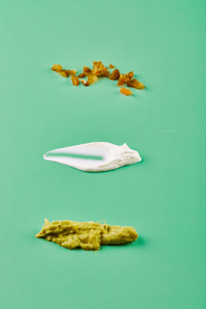 Set of different sauces - guacamole, ranch and sour cream on a green background. Set of textures of...