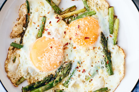 Fried eggs with asparagus and grated cheese. Breakfast concept. Top view. Close up
