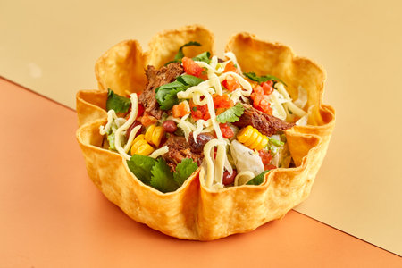 Taco salad in tortilla bowl with beef, cheese, corn and lettuce.