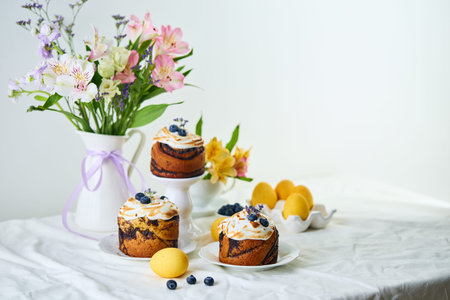 Traditional Easter cakes on festive table decorated with fresh flowers and colorful painted Easter...