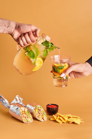 Mexican cuisine dishes, set meal of burrito, nachos corn chips and lemonade on color background