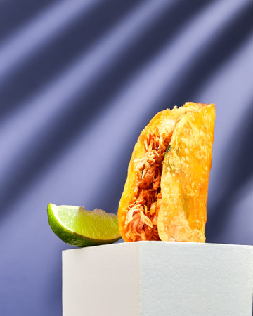 Tacos on corn tortillas with filling of beef, chicken and vegetables with wedge of lime stands on...