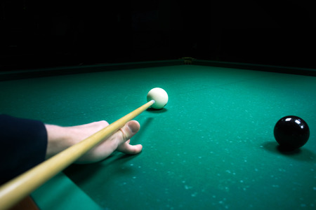 Man's hand holds a cue for striking the white cue ball. Russian pyramid (Russian billiard, pyramid billiards), cue sport.の写真素材