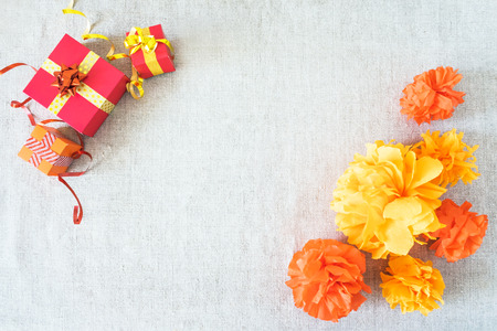 Birthday party background with festive decor, orange, yellow and red ribbons, gift boxes, balloons, garland, pompoms on neutral fabric. Colorful celebration background, copy space, Flat lay, top view.の写真素材
