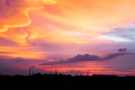 Bright purple, pink, lilac and orange sunset over city. City industrial landscape against the...