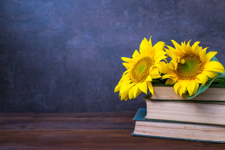 Vintage Old books and bouquet of sunflowers. Two books with bright yellow flowers. Retro nostalgic vintage background. Reading, learning, education, library concept mockupの写真素材