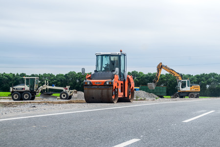 KROPIVNITSKIY, UKRAINE â 27 MAY, 2018: Road repair concept. Road construction equipment and Workers on highway. Tractors, trucks, roller on the road repair site. Fresh asphalt construction. Bad roadのeditorial素材