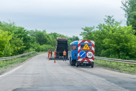KROPIVNITSKIY, UKRAINE â 27 MAY, 2018: Road repair concept. Road construction equipment and Workers on highway. Tractors, trucks, roller on the road repair site. Fresh asphalt construction. Bad roadのeditorial素材