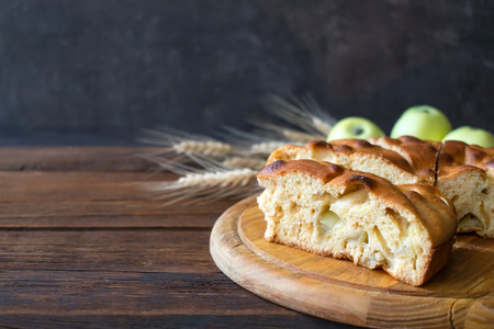 Round home-made apple pie, cobbler, brown Betty, Apple Charlotte on wooden background with apples and spikelets.の写真素材
