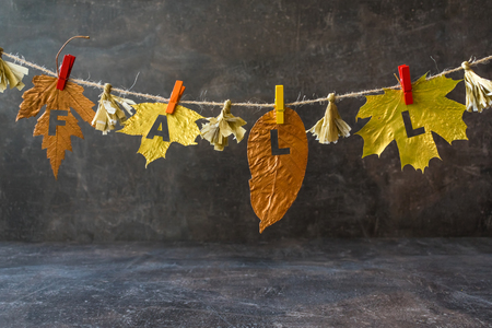 Autumn composition with golden leaves and word FALL on the rope garland. Fall mockup with different metallic paint leaves on a cord with clothespins. Flat lay, top view, copy spaceの写真素材