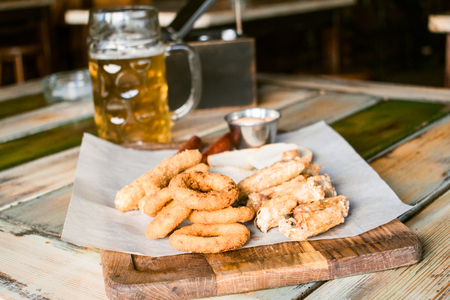 Glasses of light beer on pub background. Pint glass of golden beer with snacks and grill food on wooden table in pub, barの写真素材