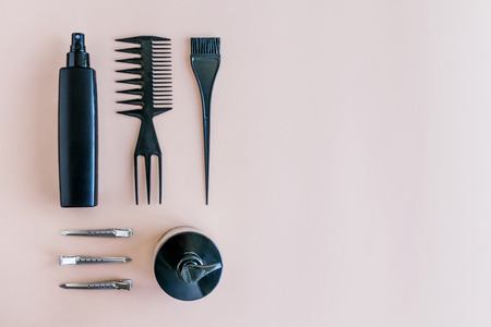 Flat lay Minimal composition with black hair salon tools on pastel background. Hair dye brush and bottle for Color Mixing. Tools for hair styling, dye and hairdye on beige background top viewの写真素材