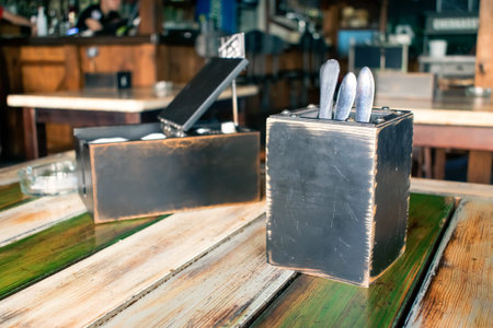 Flatware, cutlery, silverware in wooden box and Paper napkins, pepper and salt shaker on the table. Restaurant interior, pub, cafe backgroundの写真素材