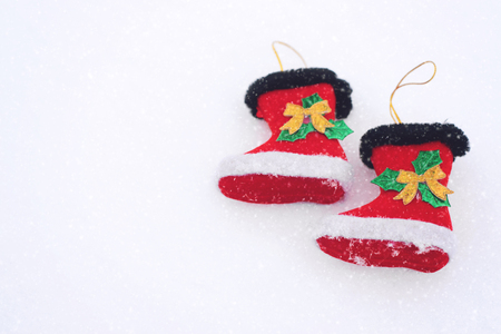 Two Red decorative christmas boots on snow white background. Christmas holiday background with Santa boots, copy spaceの写真素材
