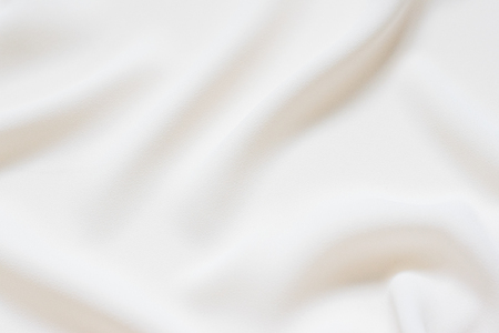 Matte cream delicate soft pleated fabric background. Smooth elegant luxury cloth texture. Gentle pastel color wedding backgroundの写真素材