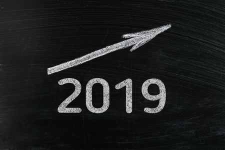 Year 2019 chalk text with a rising arrow on a blackboard. Chalkboard written with word 2019. New year success in business. Plans for the year, increase in profitsの写真素材