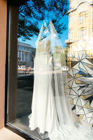 ODESSA, UKRAINE  â 22 September, 2018: Female mannequin in wedding dress in showcase. Bridal dresses Salon Showcase window display with reflections of the sky and buildingsのeditorial素材