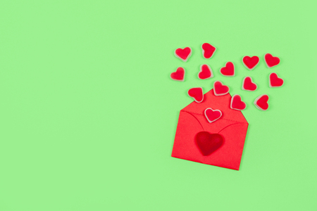 Valentines day pastel minimal creative background. Text Love is, red envelope many heart shape candies on green background. Valentines day, Love, romance conceptの写真素材