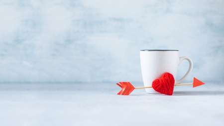 Valentines day pastel minimal creative background. Gray cup and red heart with cupid's arrow on pastel blue background. Valentines day, Love, romance conceptの写真素材