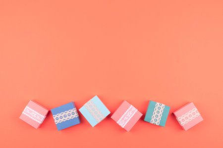 Various birthday gift boxes with lace on coral color background. Minimal concept, flat lay, copy...