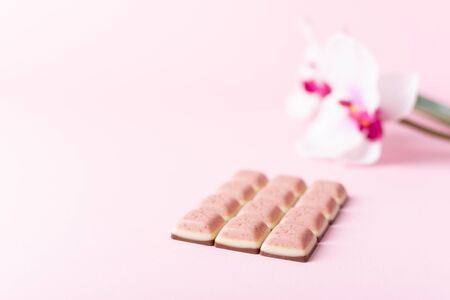 Pink chocolate bar and flower on pink background. Ruby new chocolate. New pink sweet dessert.の写真素材