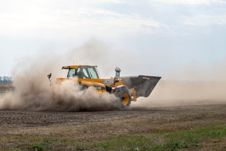 Kropivnitskiy, Ukraine April 20, 2019: The JCB bucket loader in motion at a demonstration site agro exhibition AgroExpo. Tractor rides on the field.のeditorial素材