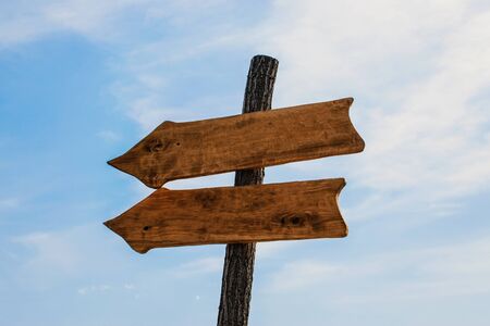 Two wooden arrow pointers mockup on blue sky background. Wooden Arrow Sign outdoor.の写真素材