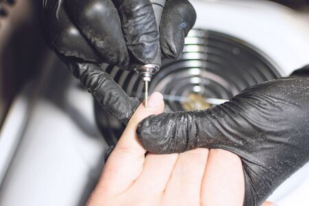 Nail Dust Collector. Combined and hardware manicure process close-up. Nail shape cuticle removal with electric nail drill.  Manicurist in rubber gloves applying electric nail file drill to female fingers.の写真素材