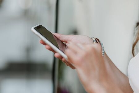 Close up Female hands with bracelets holding smartphone. Woman hand holding mobile phoneの写真素材