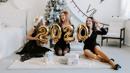 Happy girls friends holding 2020 golden balloons at New Year party, having fun together. New Year Eve 2020 partyの写真素材