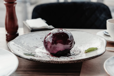 Sphere shaped mousse glazed dessert, cheesecake with chocolate and mint on the white plate....